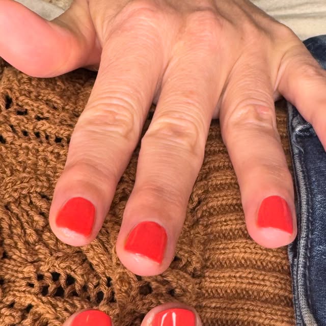 A CND Vinylux manicure in a bright coral red